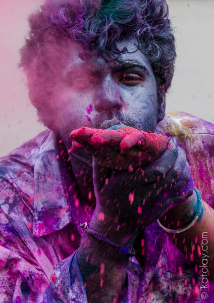 A person blowing purple powder at the camera