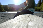 A woman sitting on a log near a river