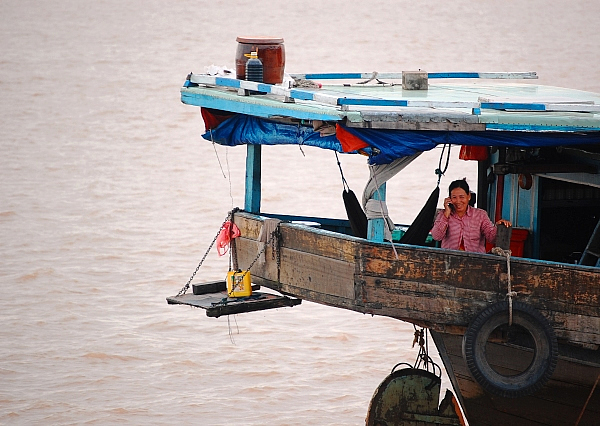 Woman using cell phone on the Mekong River, Cambodia