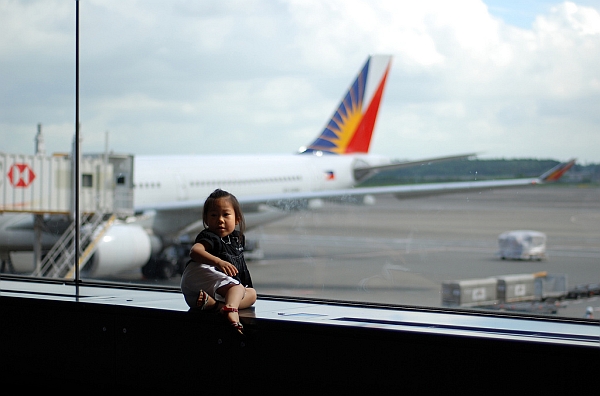 child playing at airport with plane in background