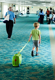 child with green suitcase in airport