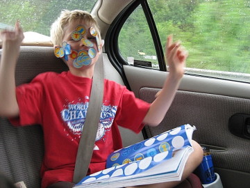 a child lonesome with stickers acting stupid in the automobile during the main road trip