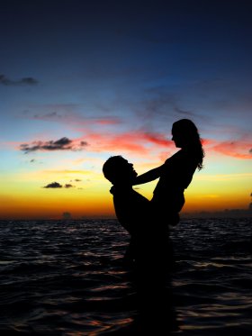 Couple embracing in the waves at sunset