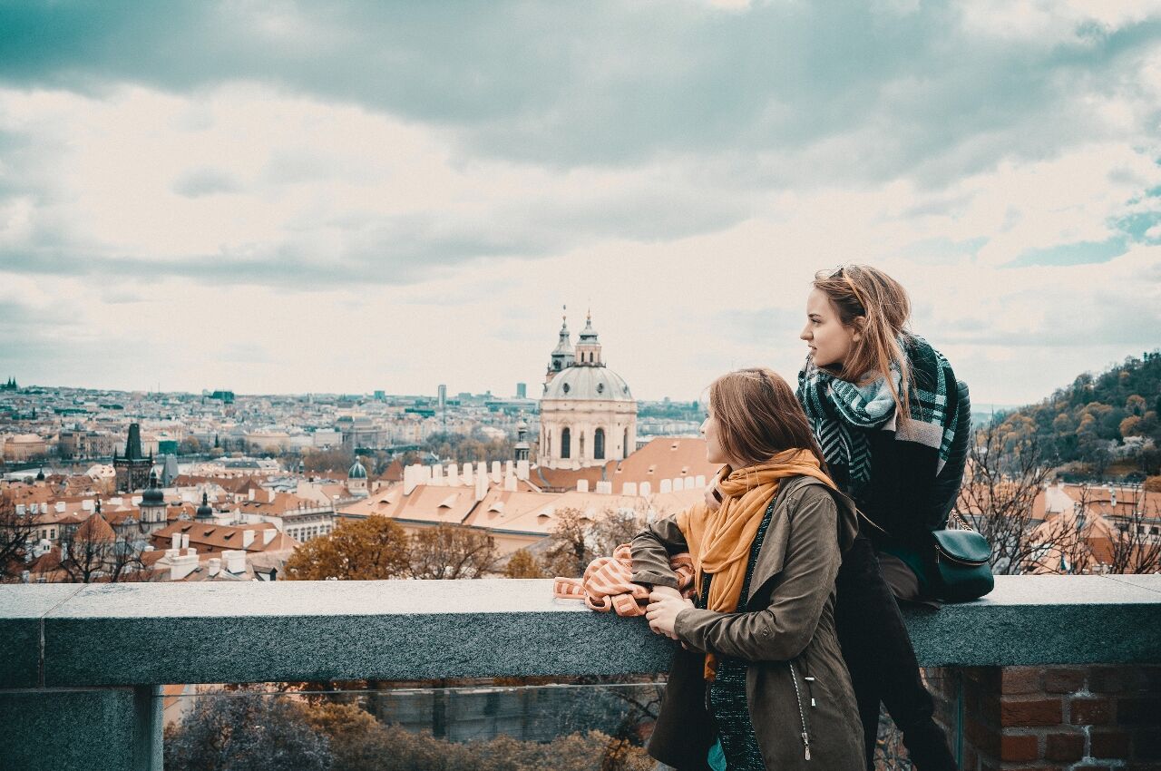 Two women look over wall in Prague 