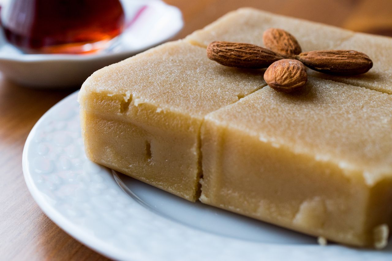 Brown squares of halva topped with almonds on a plate