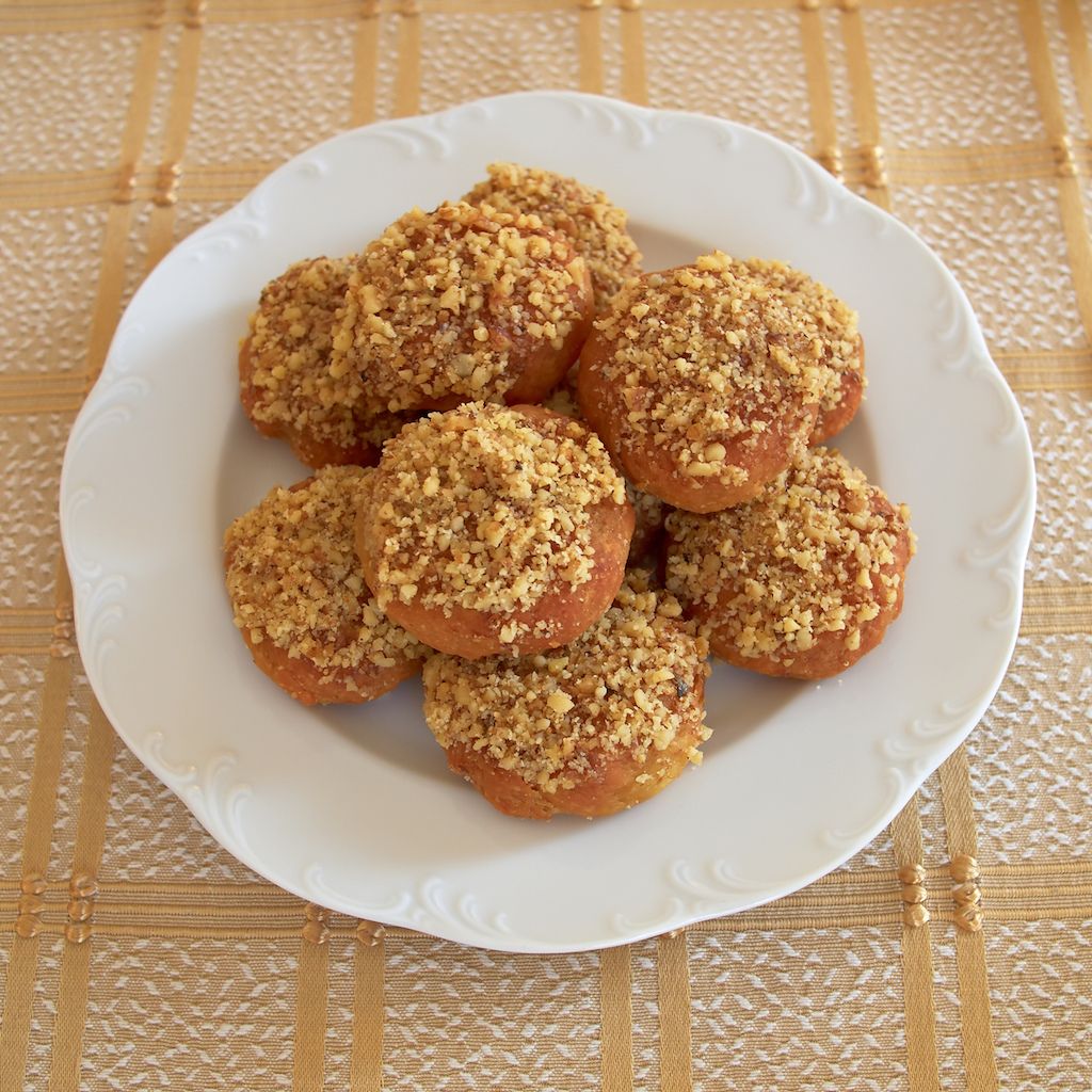 Melοmakarona cookies topped with chopped walnuts on a white plate