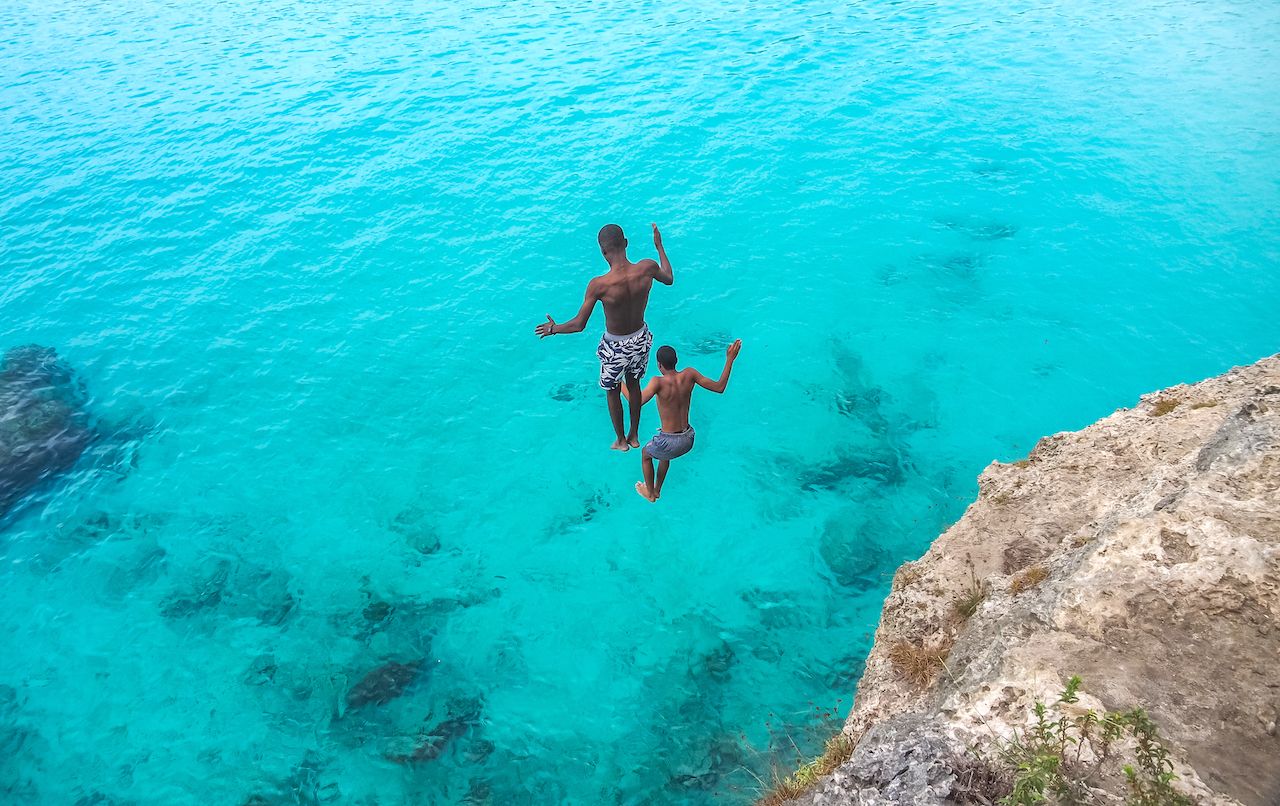 Cliff jumpers diving into turqoise water in Curacao