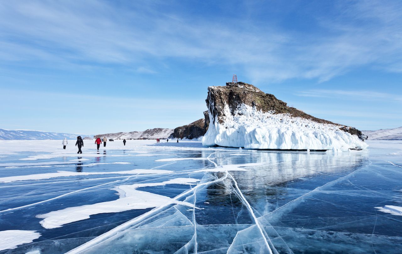 A group of tourists travels along the ice of Lake Baikal