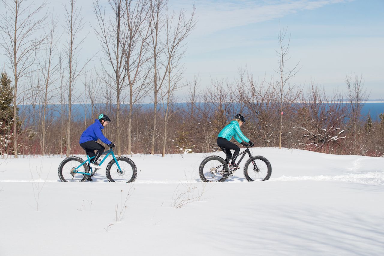 A couple rides their fat bikes on a trail in the snow