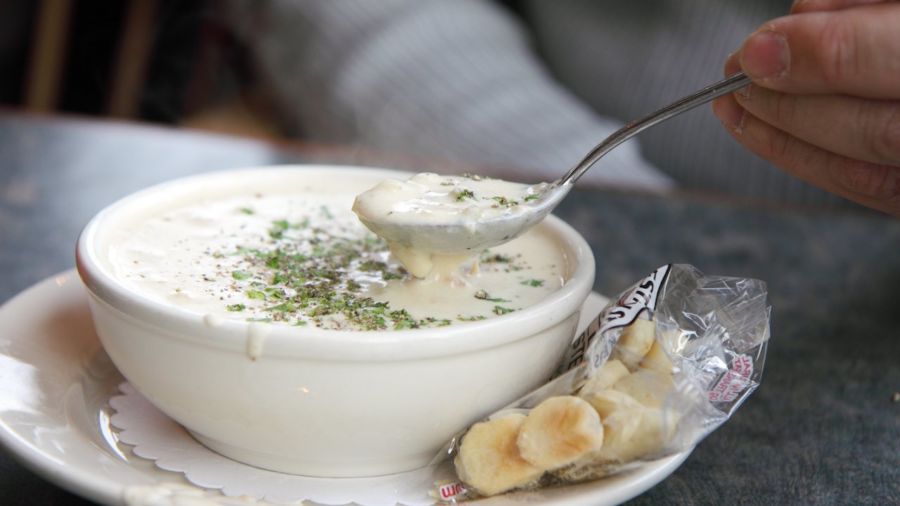 Steaming bowl of New England clam chowder with crackers on the side
