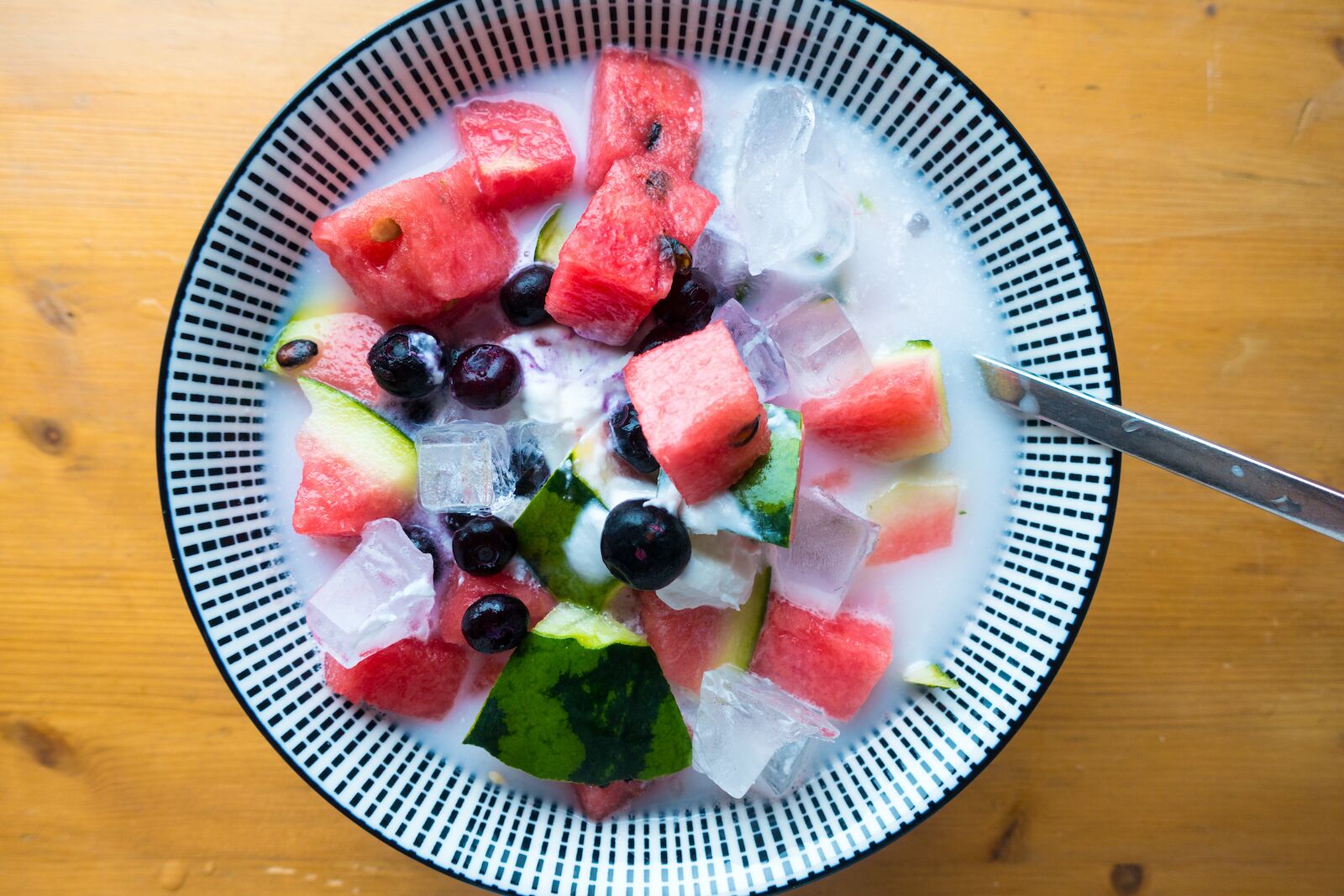 Hwachae, or watermelon punch, with milk and other cut up fruits, in a blue bowl