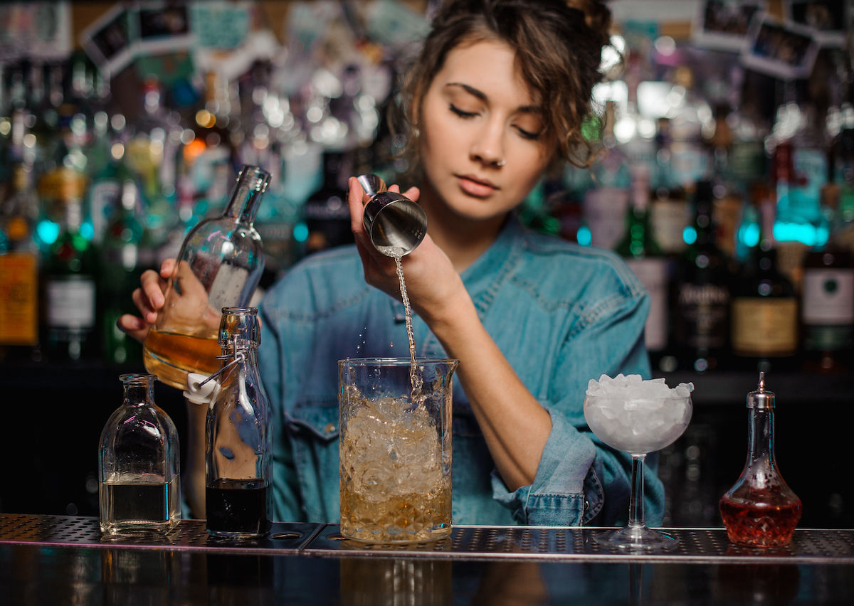 Young female bartender using cocktail shaker - Stock Photo - Dissolve