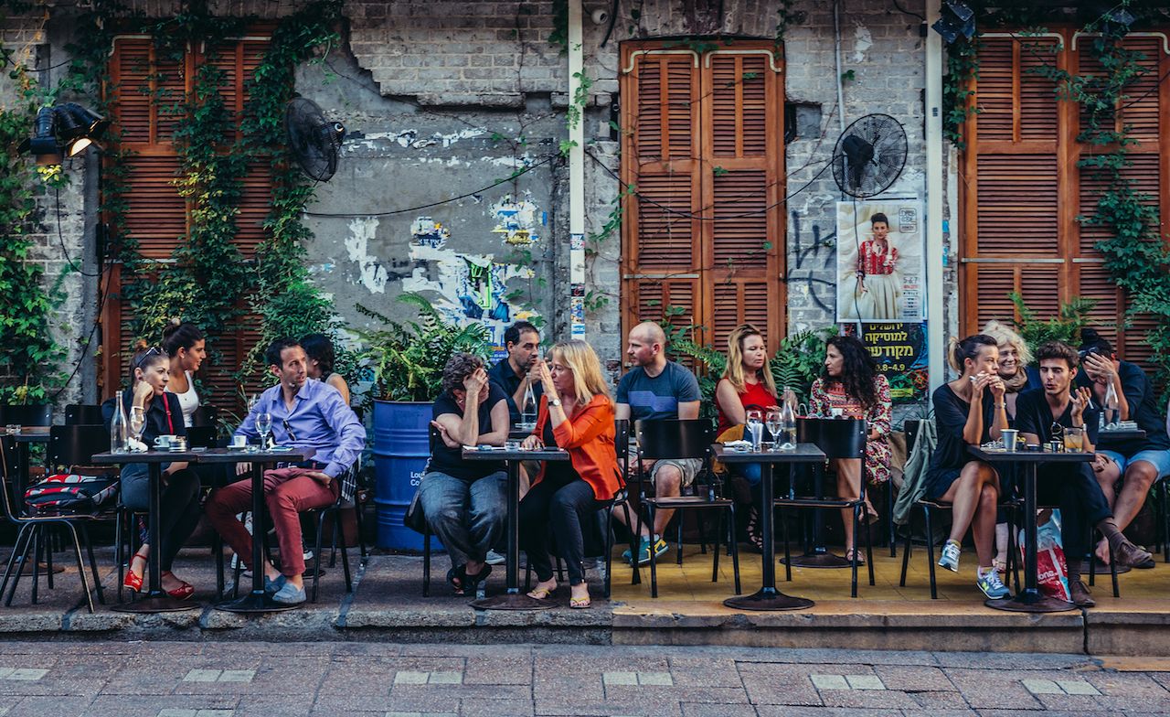 People sits at tables outside the restaurant at Rothschild Boulevard in gay Tel Aviv