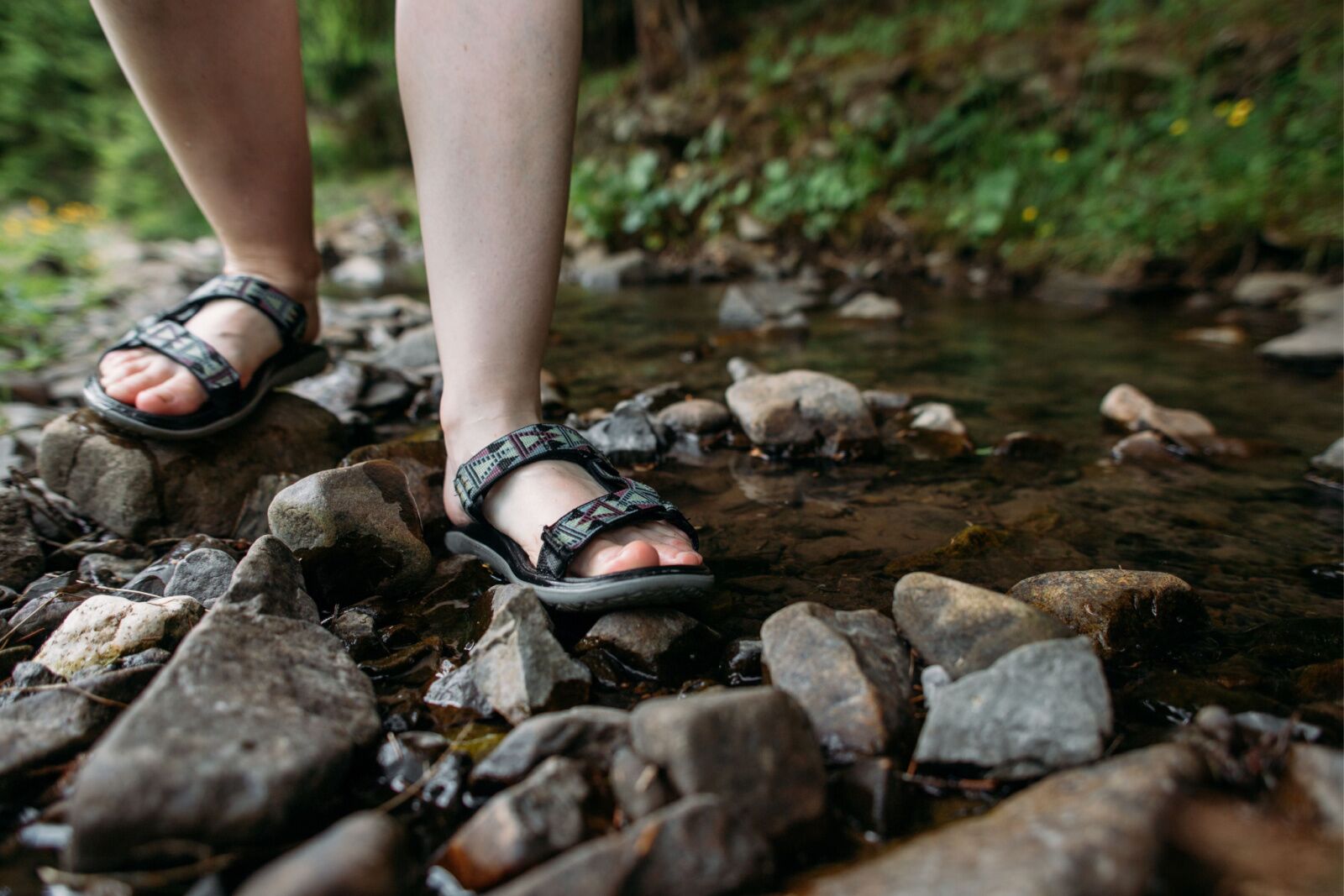 Close up of someone wearing hiking shoes for hawaii doing a stream crossing 