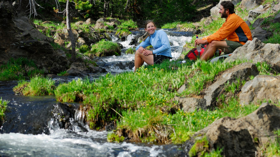 Hiker couple resting by a cold mountain stream Bend, Oregon, United States