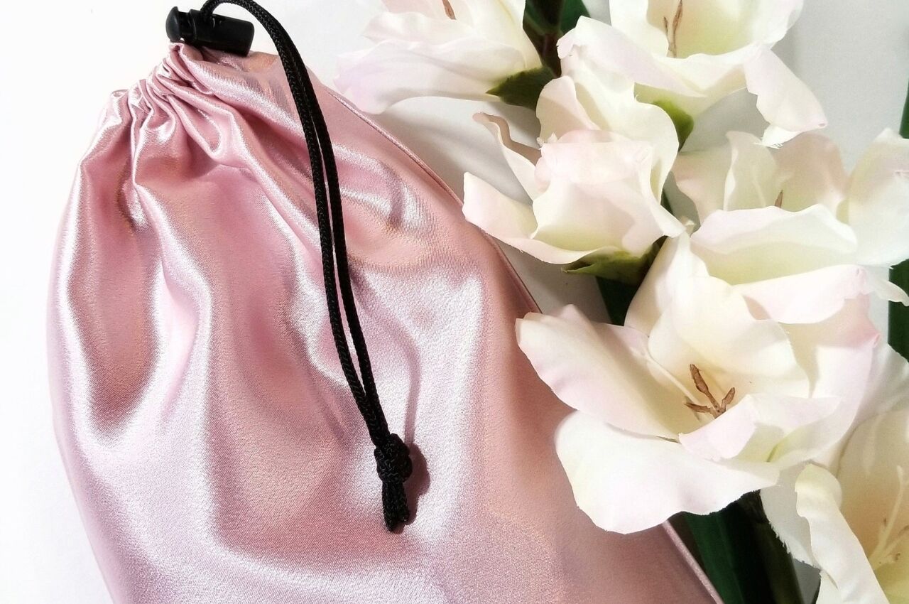 Pink silk bag for sex toys beside while orchids