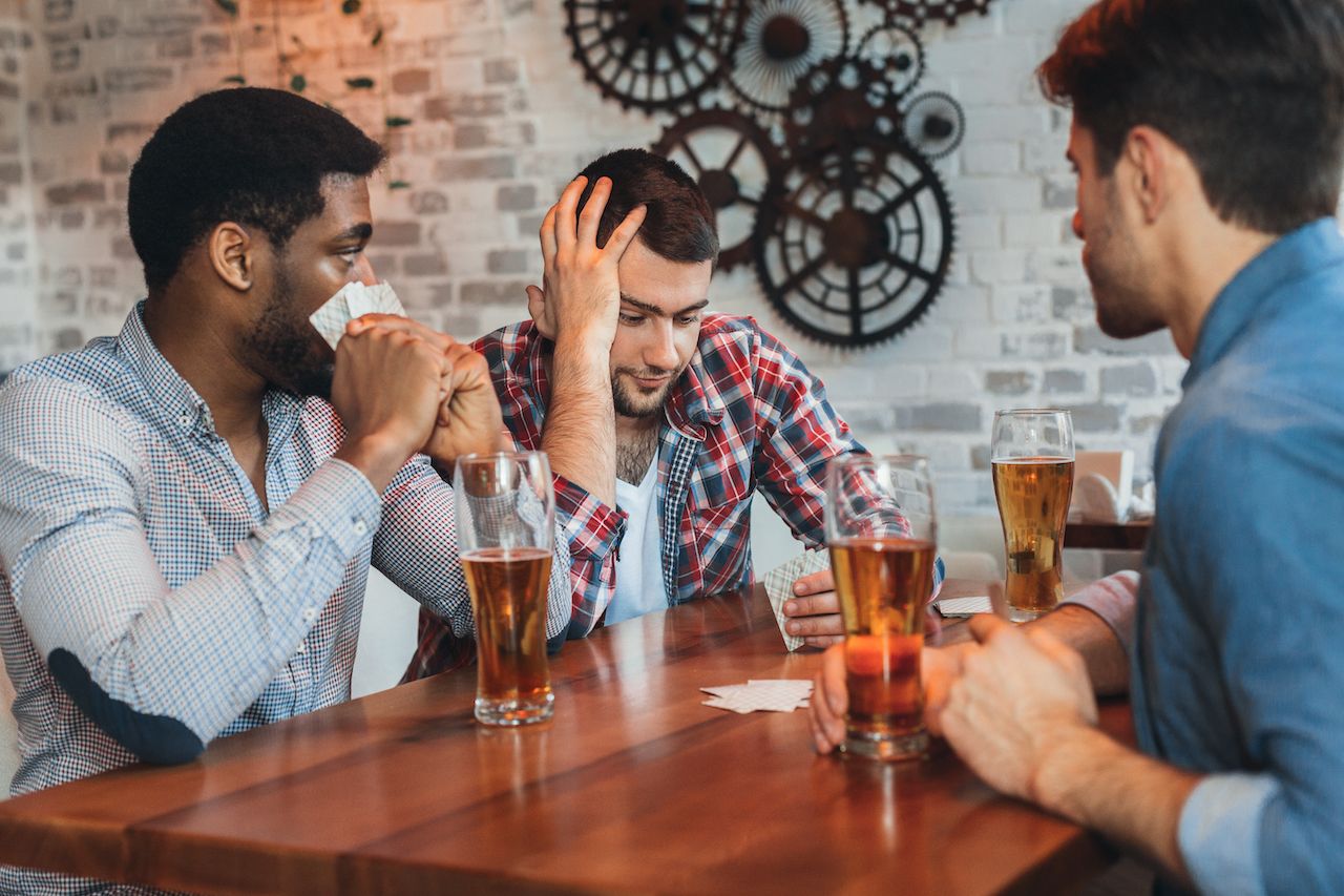 People at a bar with beer glasses playing drinking card games