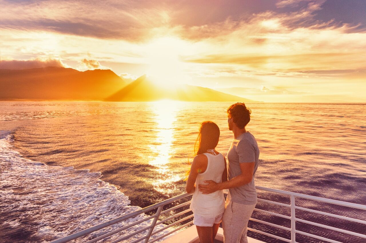 Couple on swingers cruise ship looking at sunset from side of cruise ship