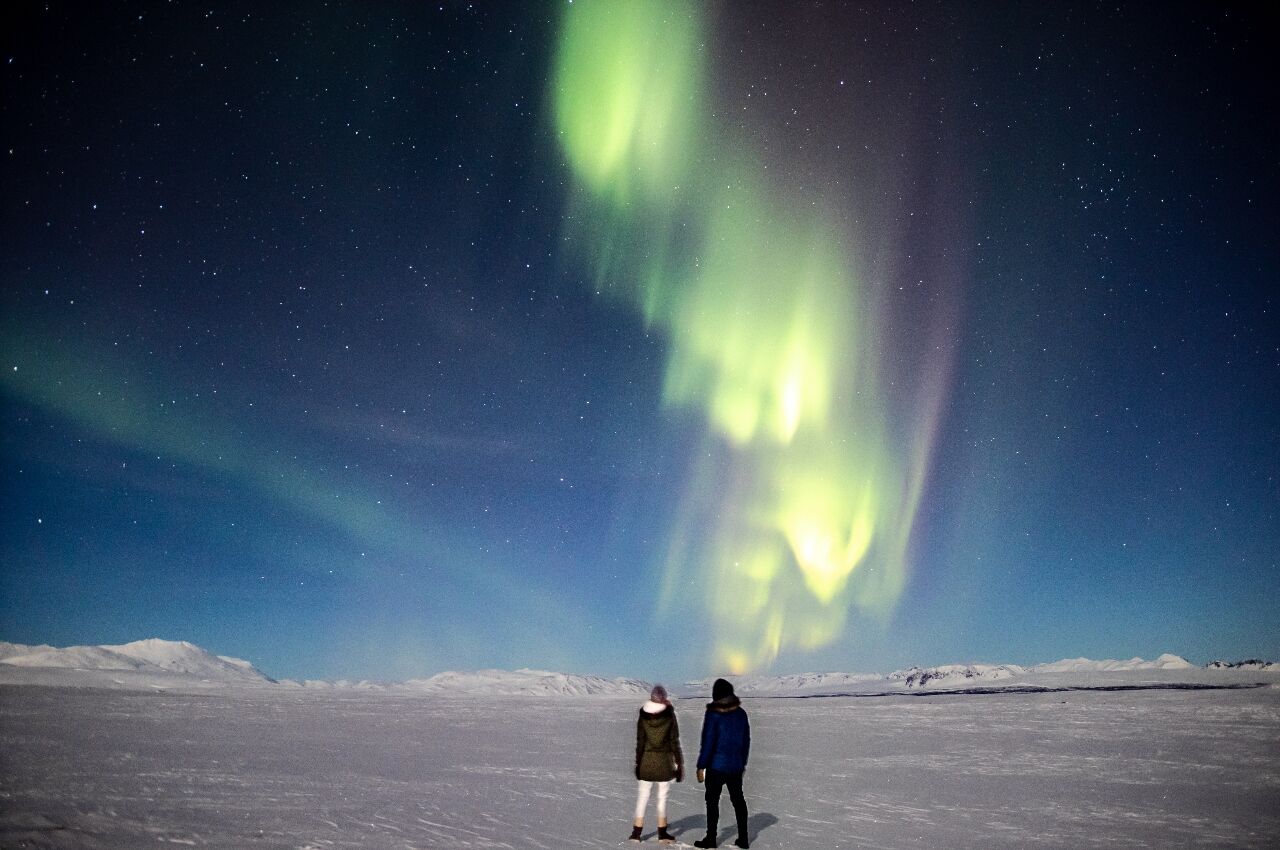 couple on beacation in winter watching northern lights