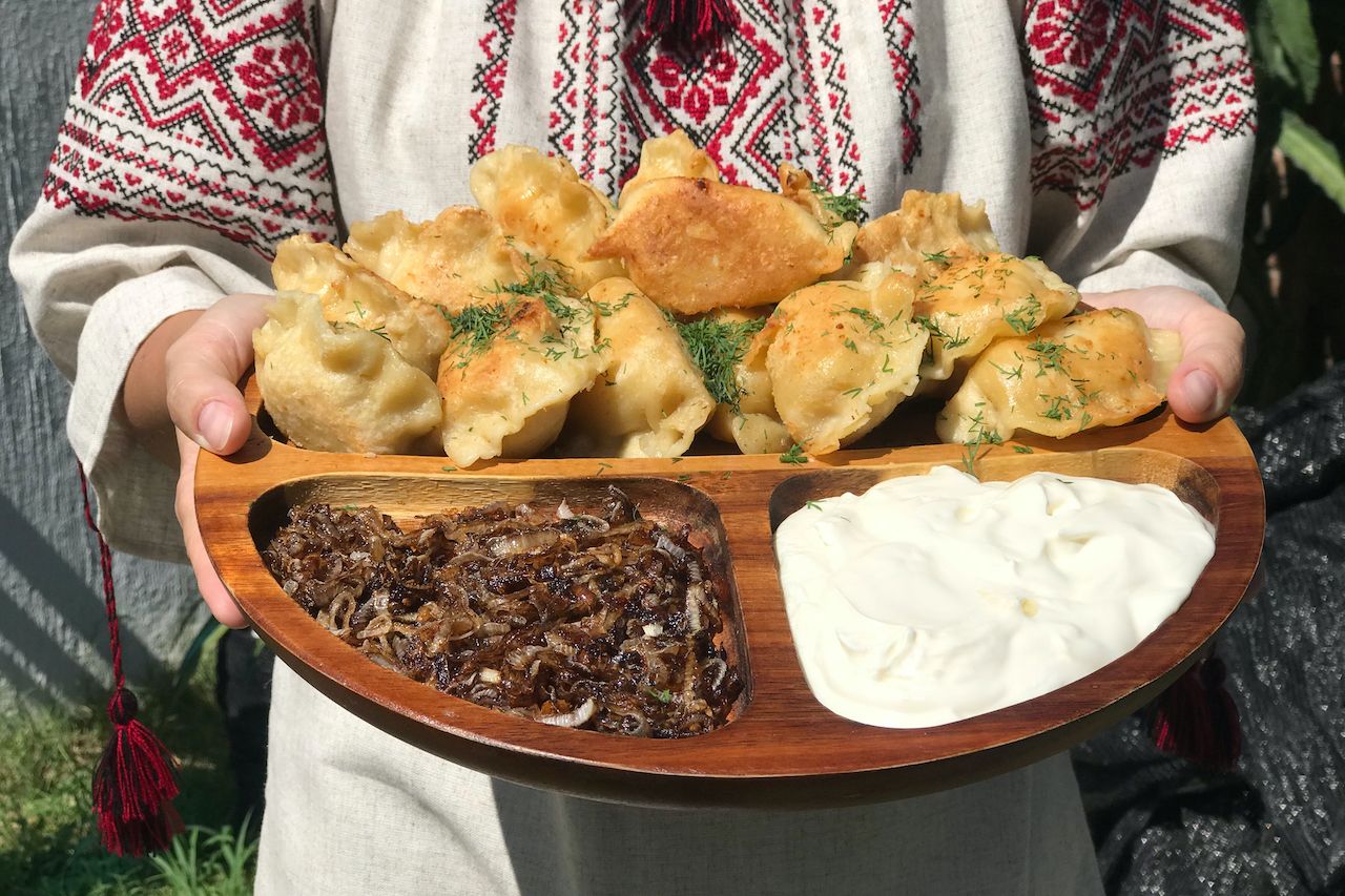 traditional ukranian food on a dish held by a woman 