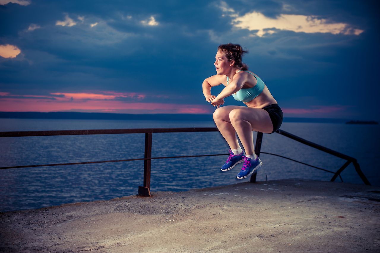 Person in sportswear doing plyometric exercises on pier