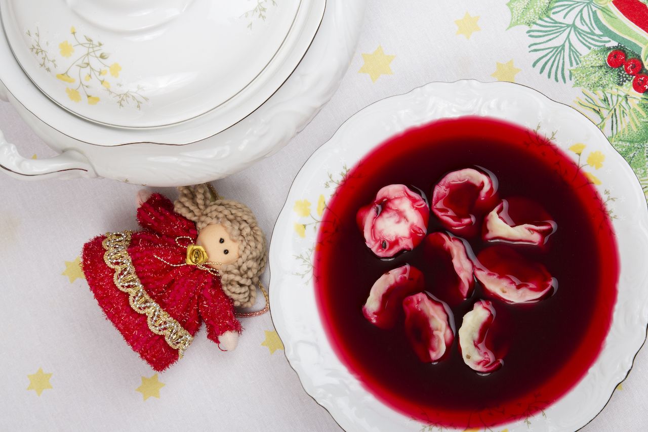A bowl of red borsch on a table with a Christmas tablecloth