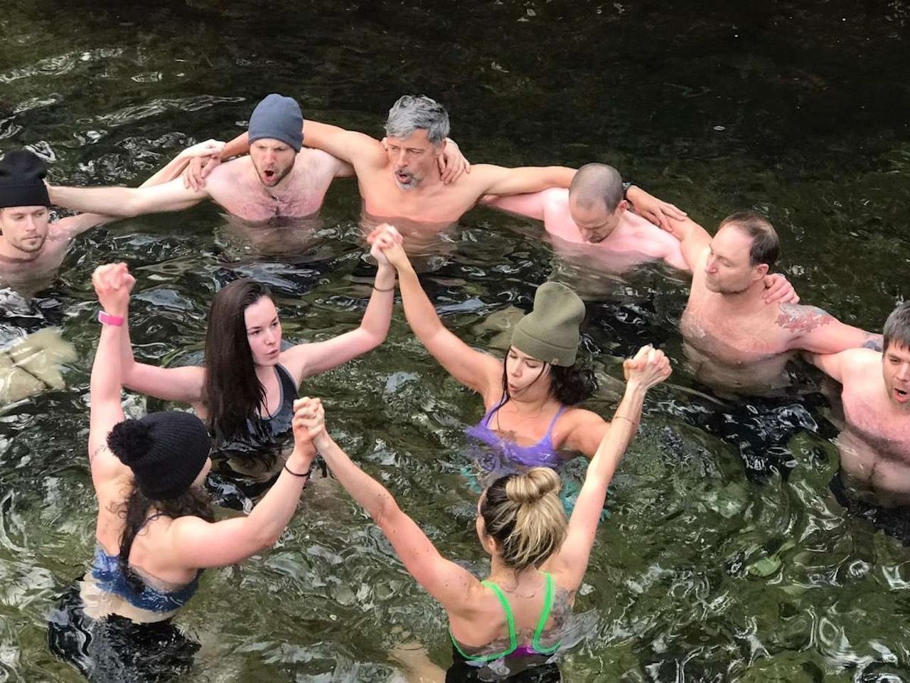 people in water holding hands practicing wim hof method