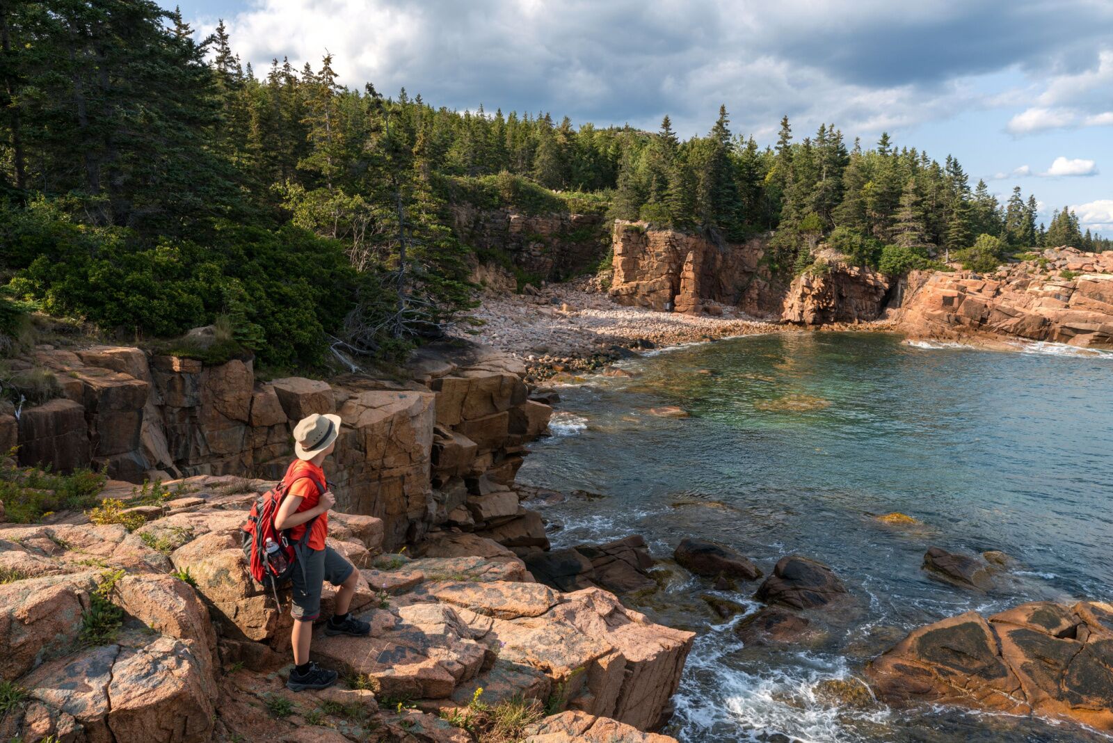 Person standing on rocks looking out at ocean in Acadia National Park