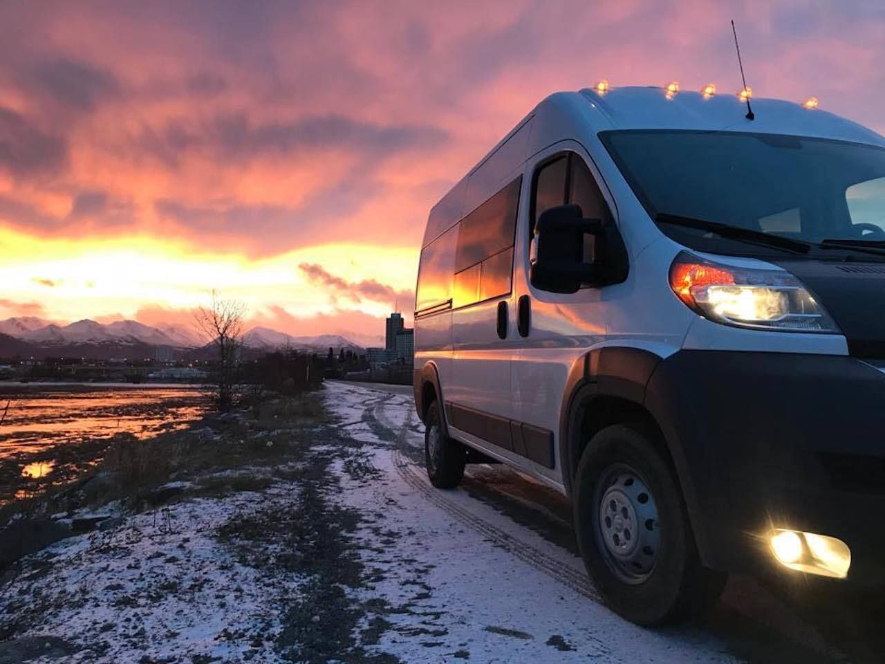 A white Ram ProMaster 1500 high roof 4x4 camper van at sunset