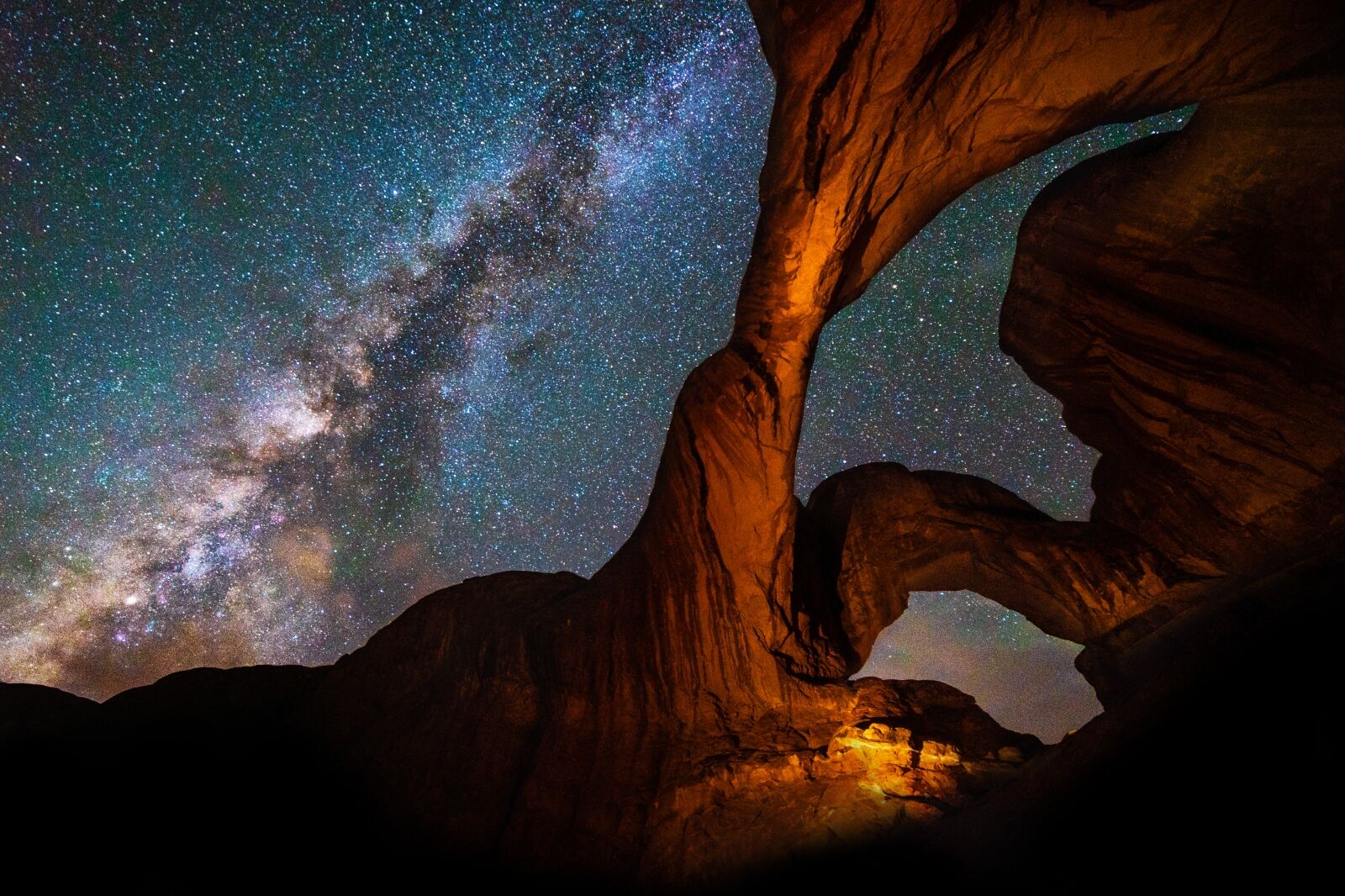 Milky Way Galaxy behind Double Arch sandstone rock formation in Arches, National Park, Utah one of the best places for camping at night 
