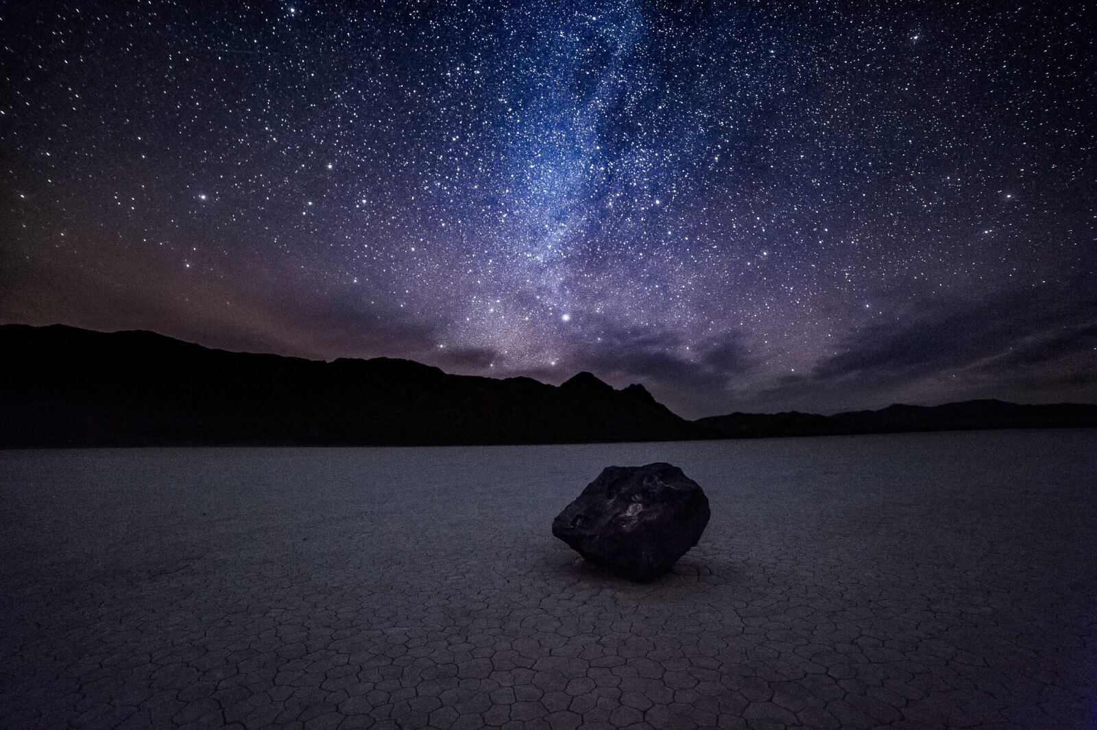 Night sky and the milky way over a moving rock at the Racetrack in Death Valley National Park in California one of the top stargazing camping sites in the US 