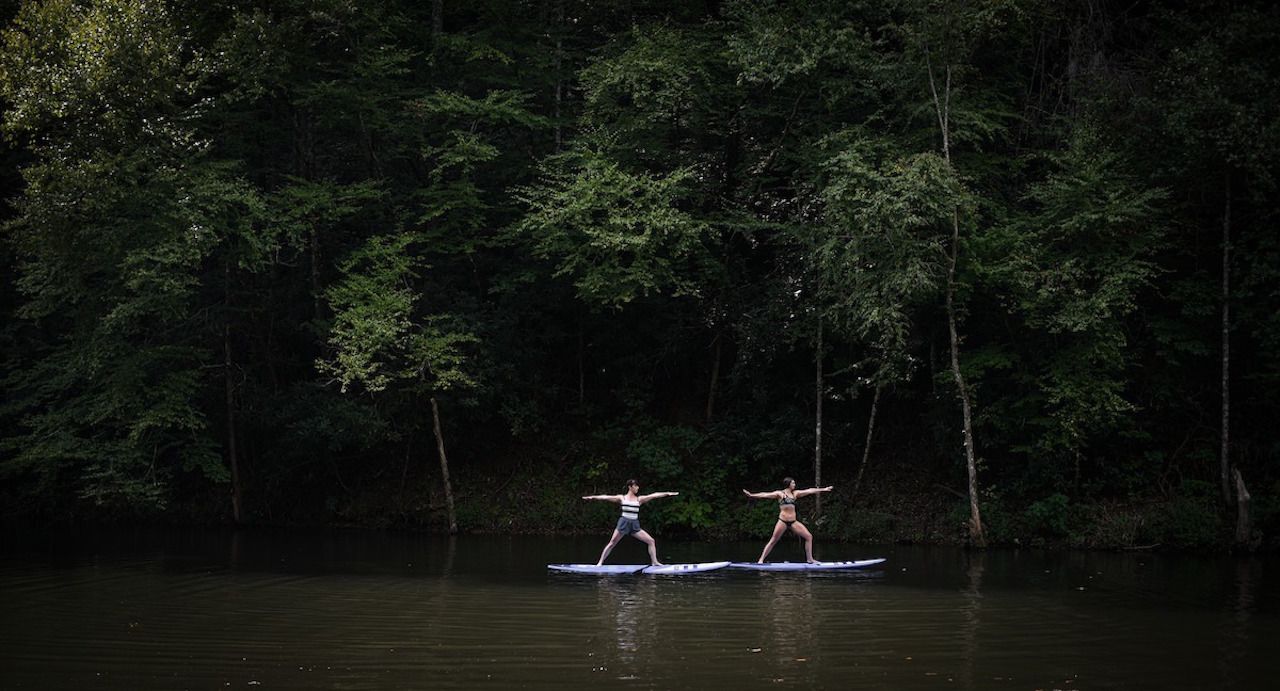 Guests practice stand-up paddleboard yoga at Blackberry Mountain wellness retreat