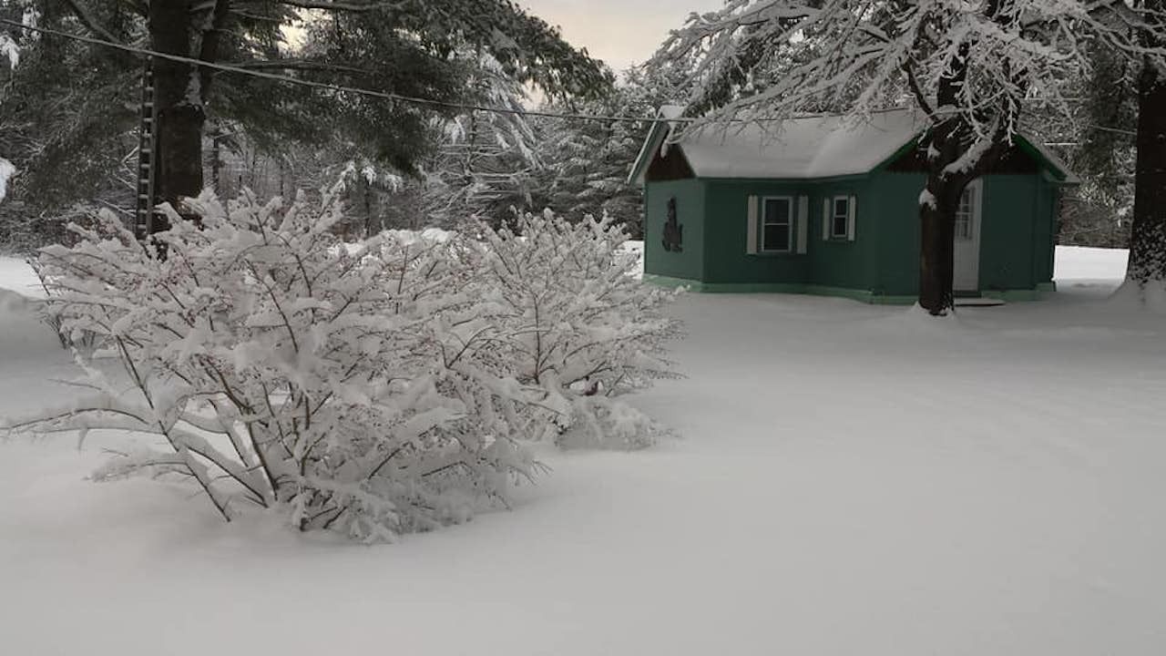 A green cabin surrounded by snow in New Hampshire