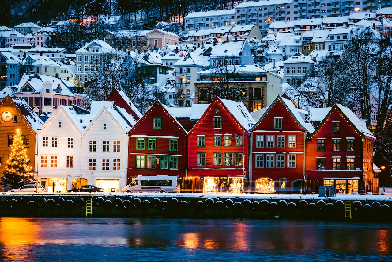 A line of red and white houses decorated with Christmas lights as seen from the harbour of Bergan, Norway