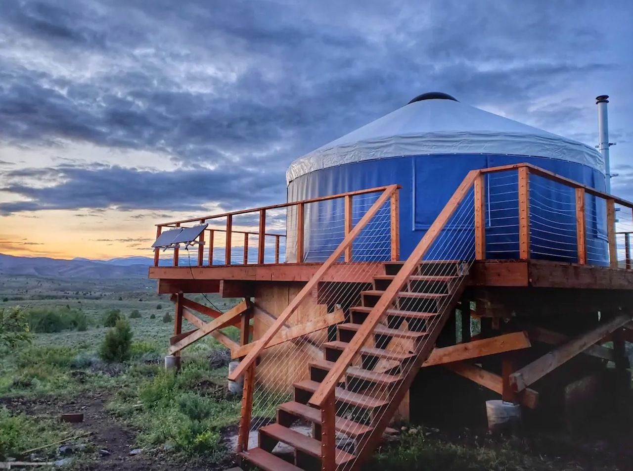 A yurt on an elevated platform in a green field in Utah