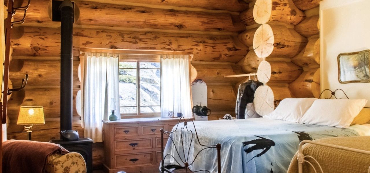 A rustic bedroom in Hideout Lodge with log walls 