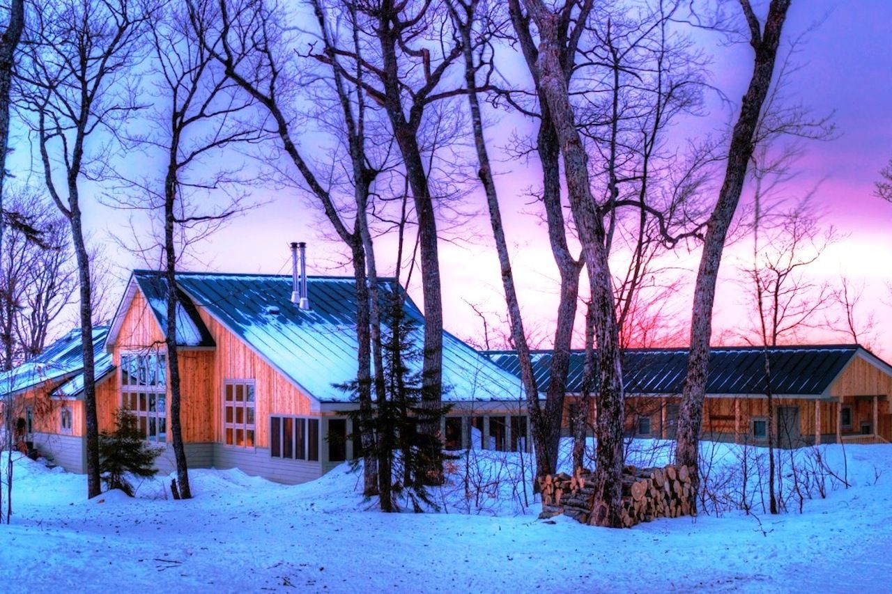 The exterior of Stratton Brook Hut in Maine with the sunrise in the background