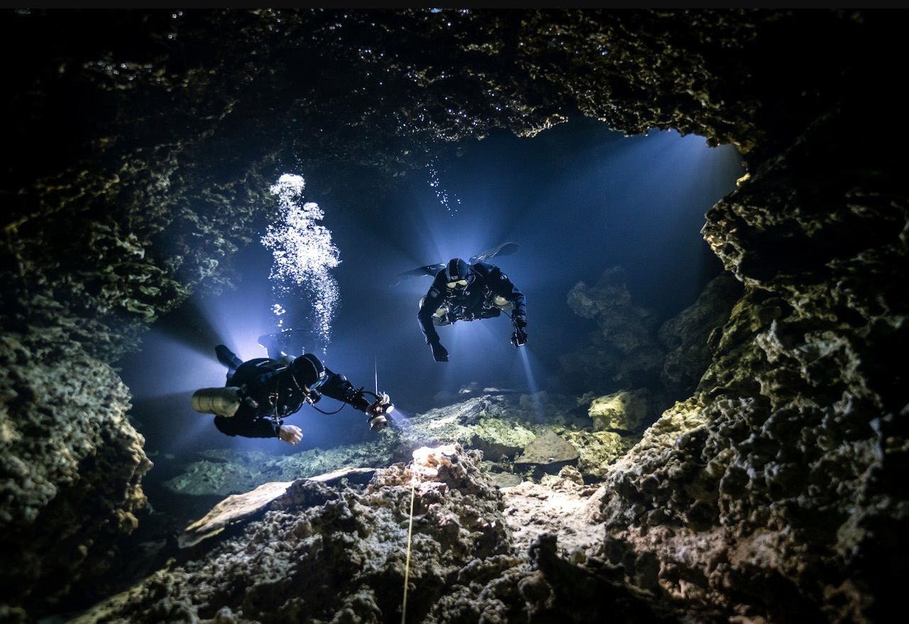 scuba divers in a cave