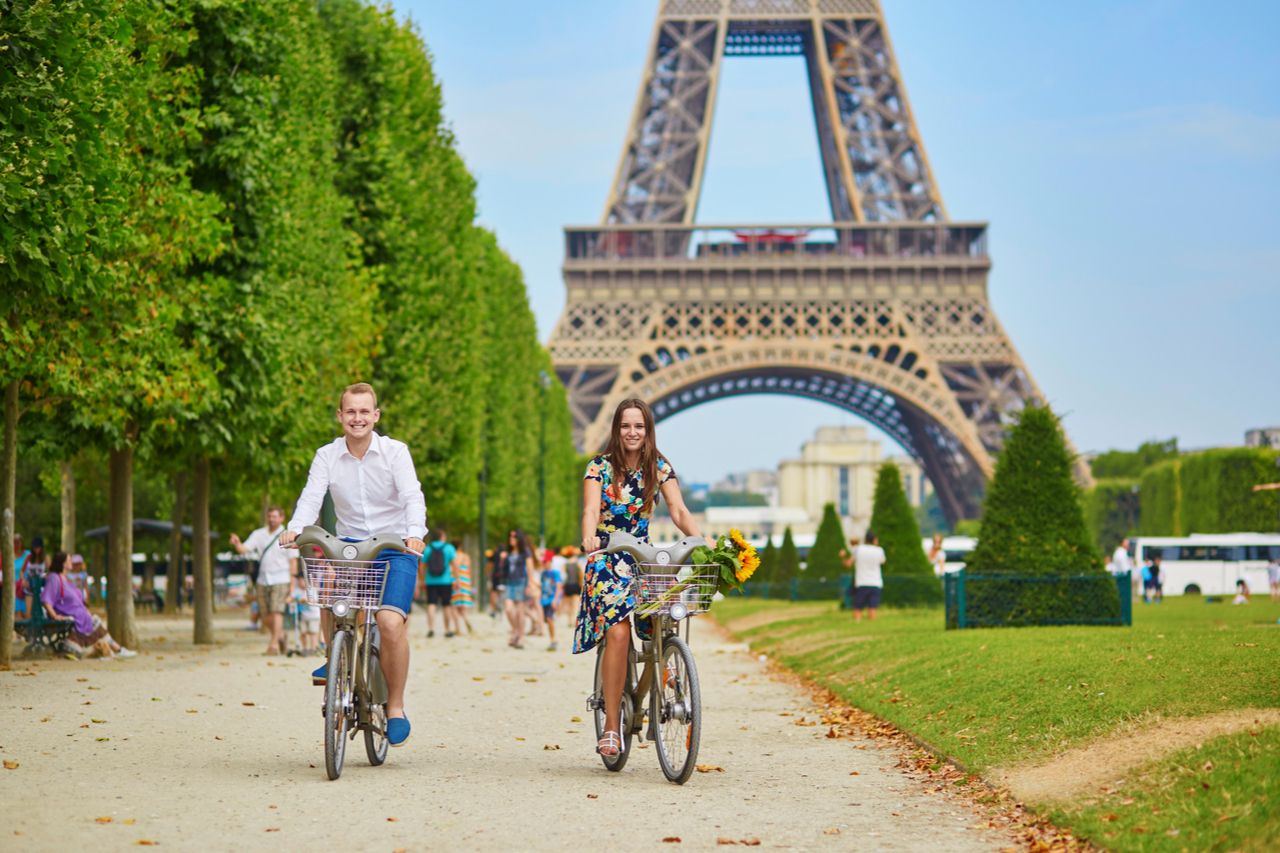couple riding bicycles near the Eiffel tower in Paris, France vaccinated Americans