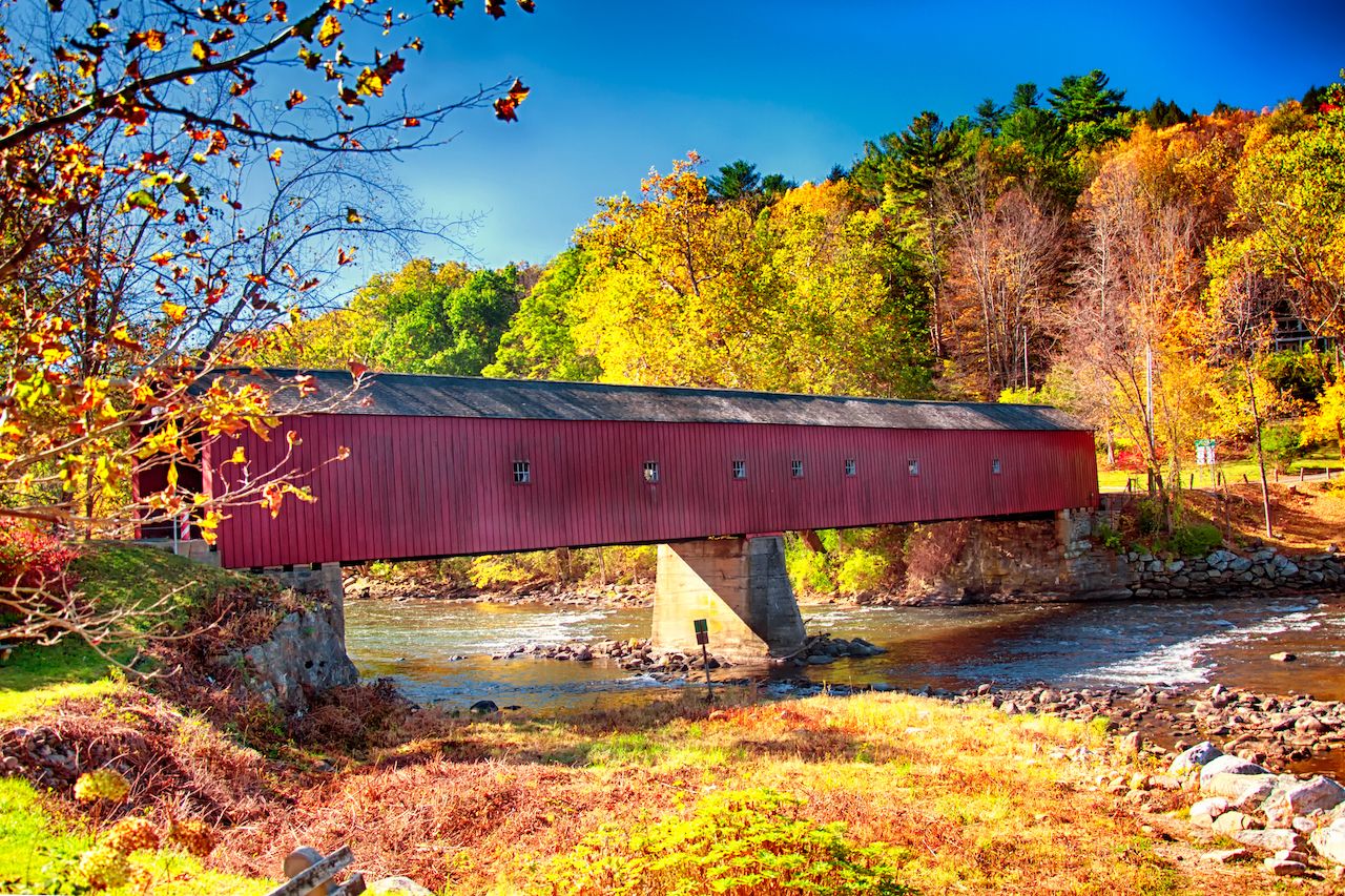 A iconic west cornwall covered bridge spanning the Houstanic River in Connecticut during the new england autumn.