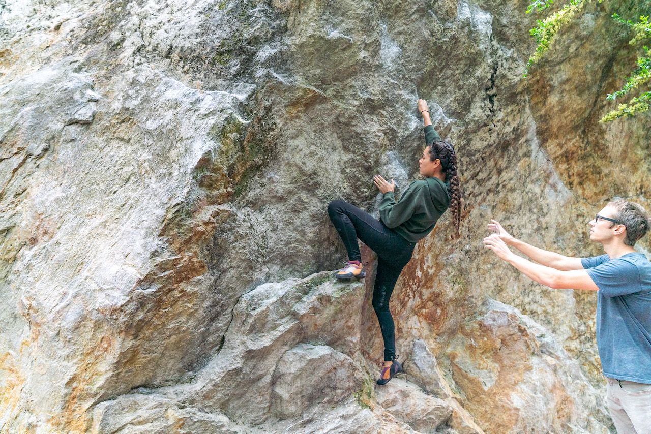 Young woman tackles a boulder at Indian Rock - climbing San Francisco