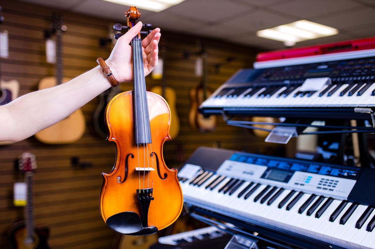 person holding a violin in a music shop