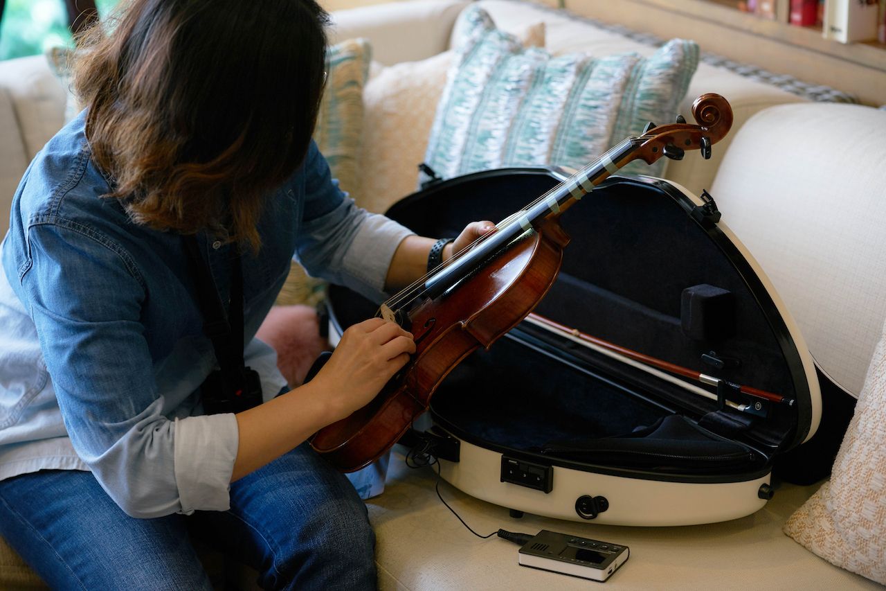 Woman prepares violin in hard)shell case before traveling