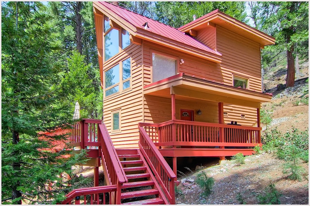 A yellow cabin with a red porch in the woods near Yosemite National Park