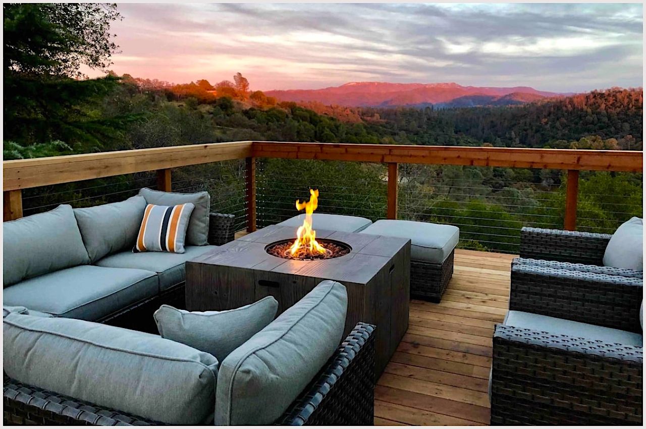 An outdoor seating area with a fireplace overlooks the hills near Mariposa