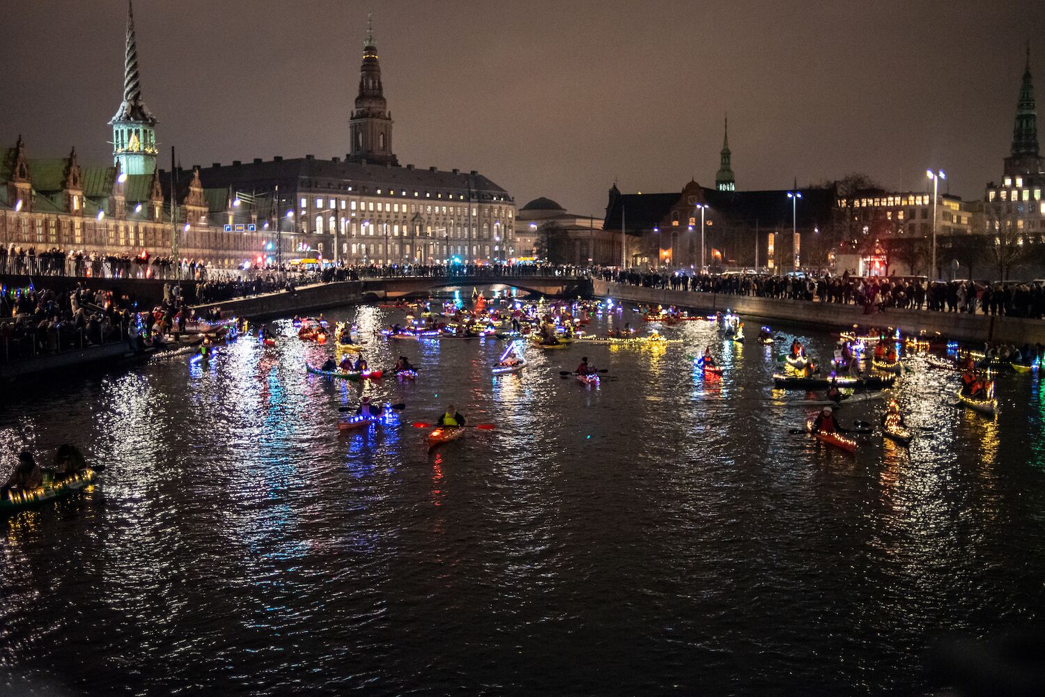 Danish people kayaking on Copenhagen's canals with lights and decorations on their boats