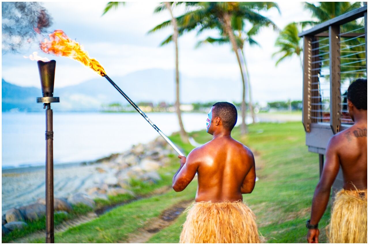 men lighting torch on Fiji vacation 