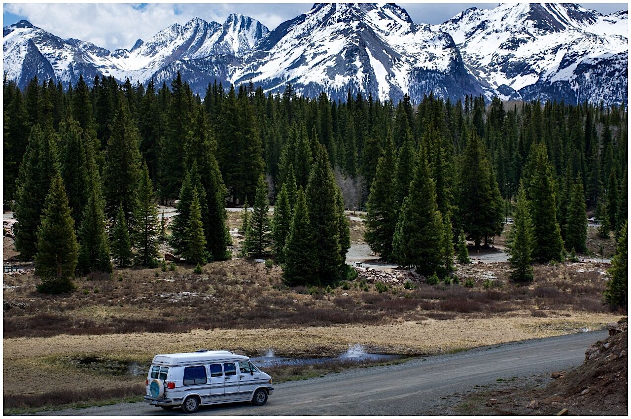 Van life van drives on road near forest and mountains