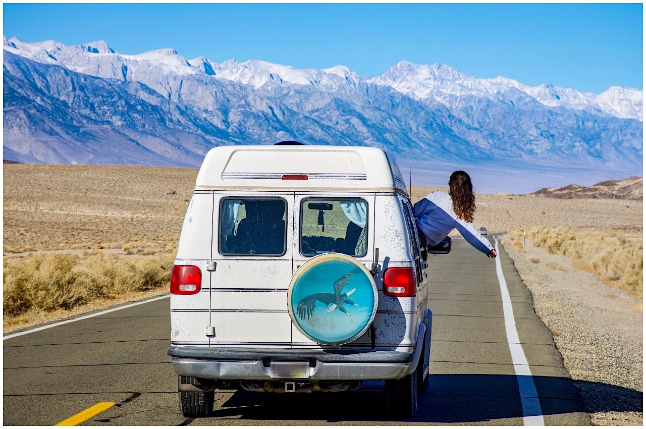 Girl hangs out of white van living van life in the US