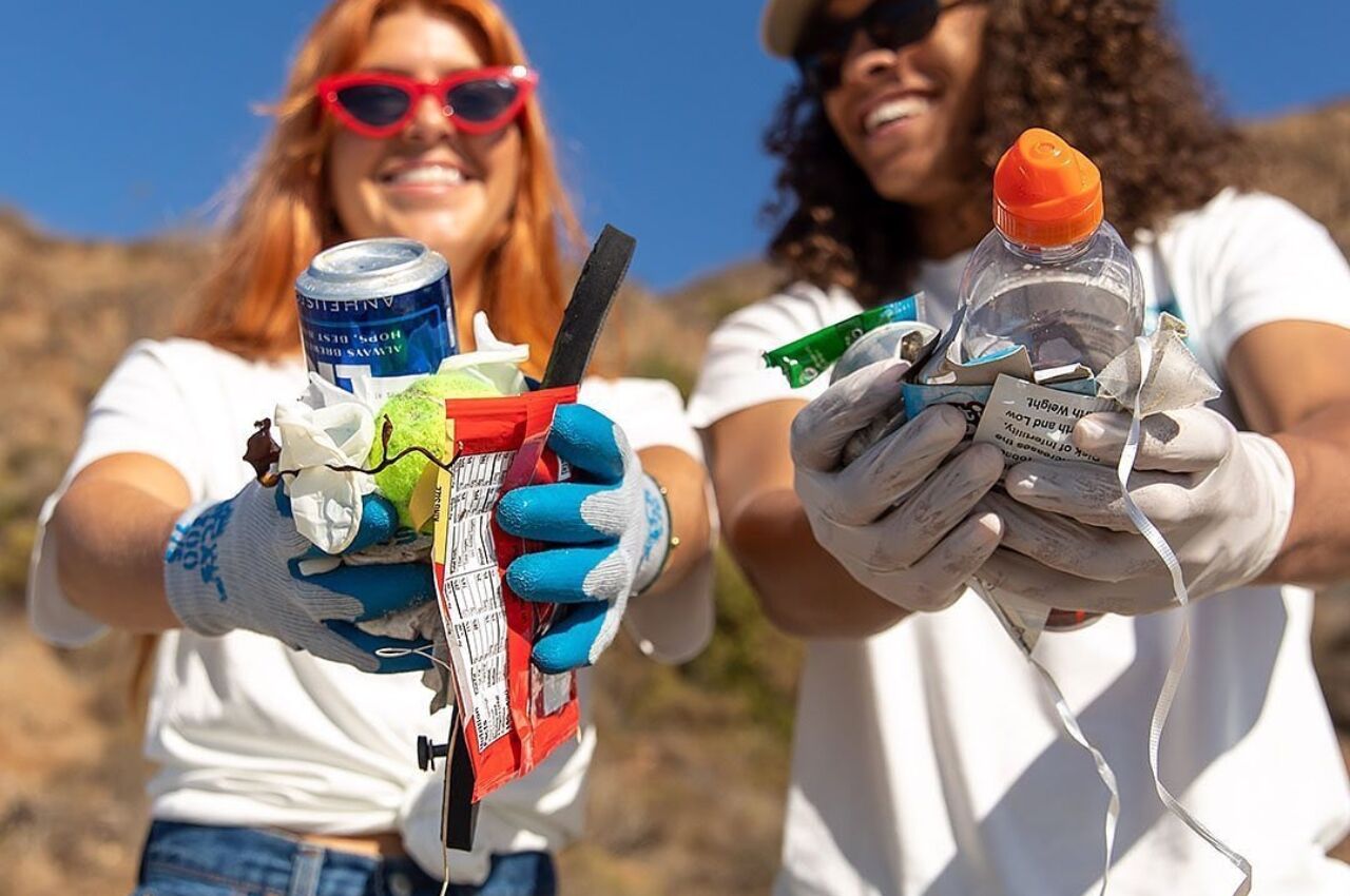 Two women volunteers holding garbage collected from a beach cleanup in Hawaii 